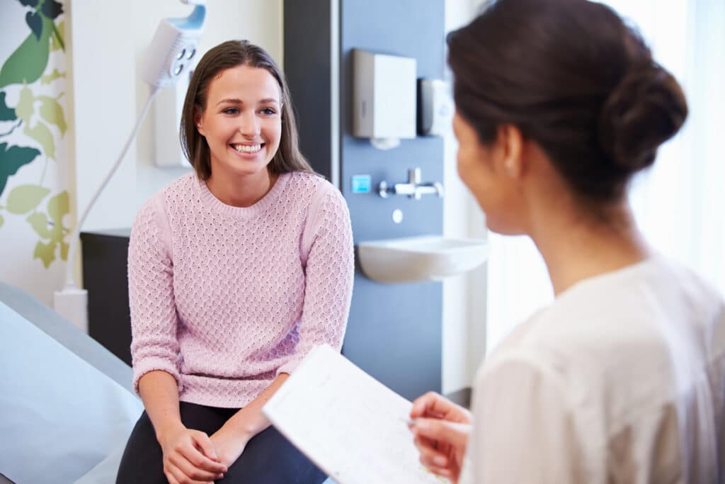 Female Patient And Doctor Have Consultation In Hospital Room